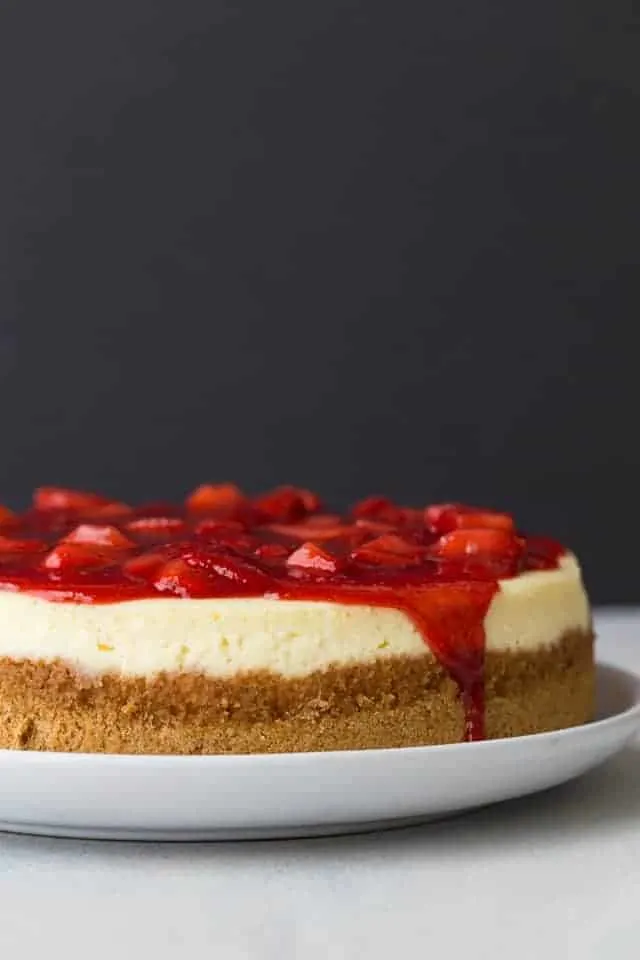 cheesecake topped with strawberry sauce on white plate