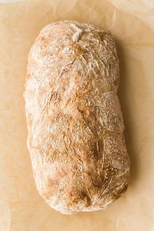Overhead view of a loaf of ciabatta bread on brown parchment paper.