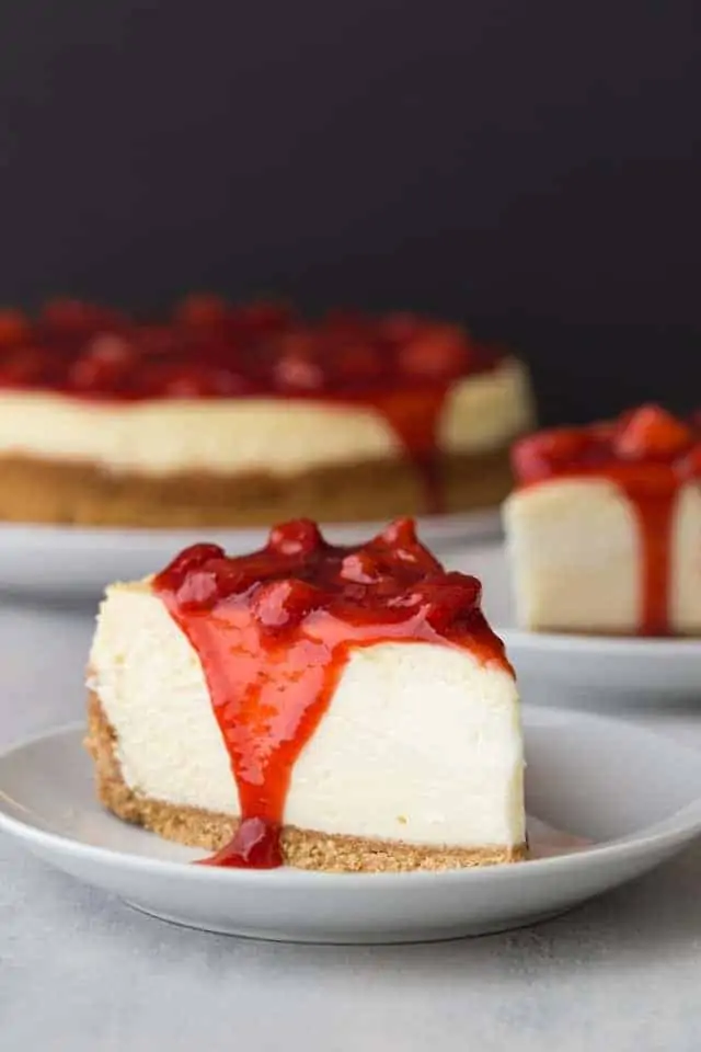 side view of slice of strawberry cheesecake on white plate