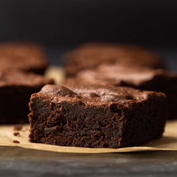 one chocolate brownie sitting on brown parchment paper