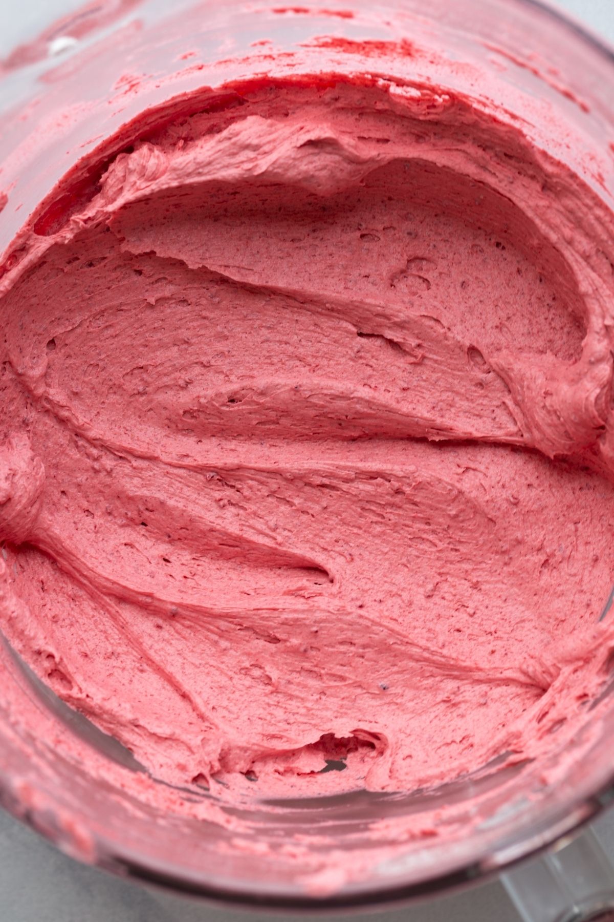 Raspberry frosting in a glass mixing bowl.