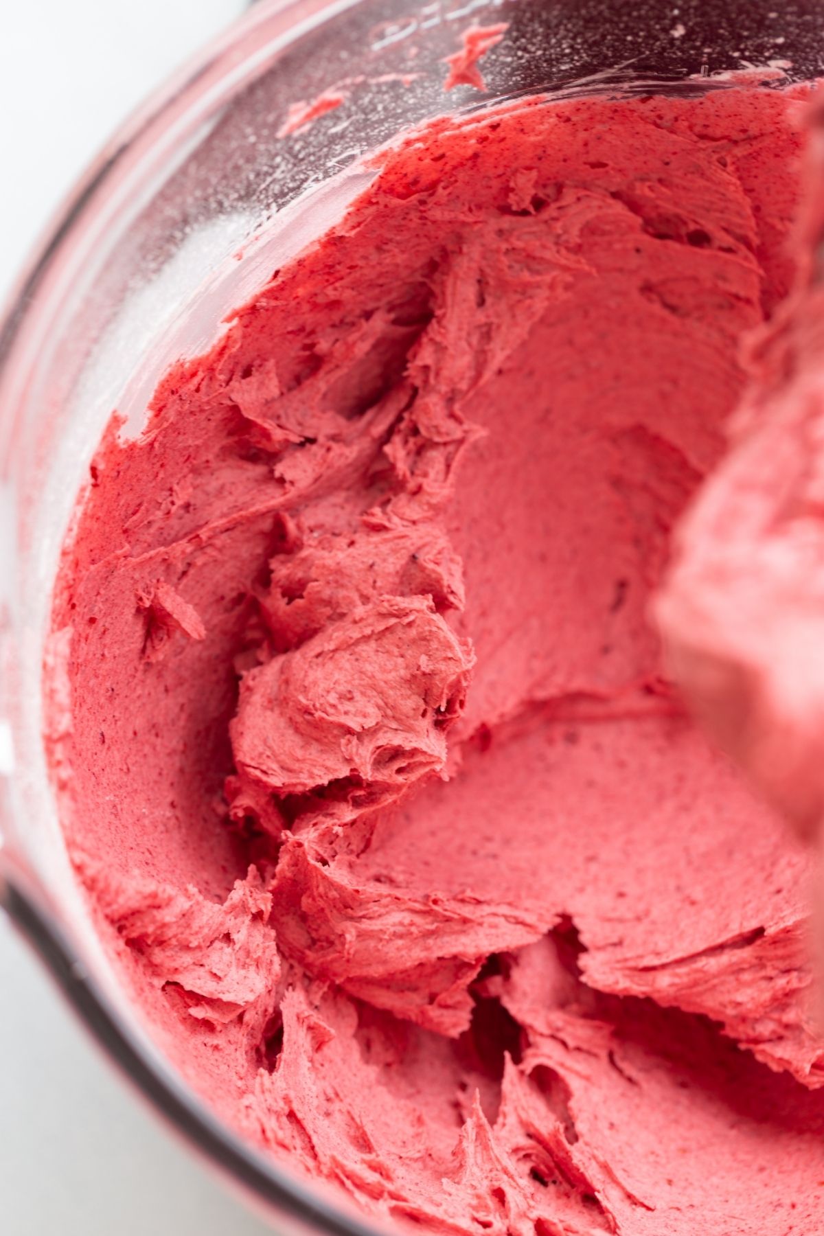 angled view of raspberry frosting in a mixing bowl