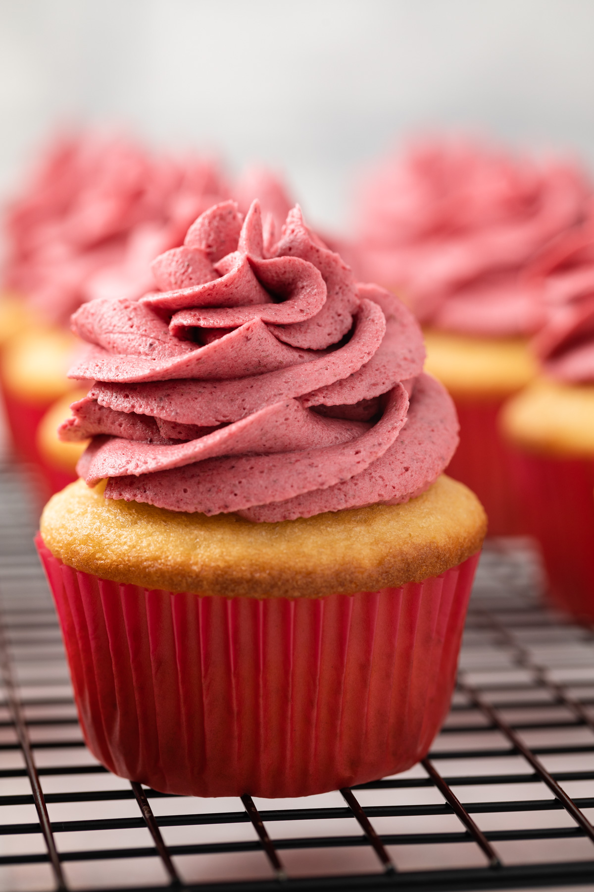 Raspberry frosting swirled on top of a yellow cupcake.