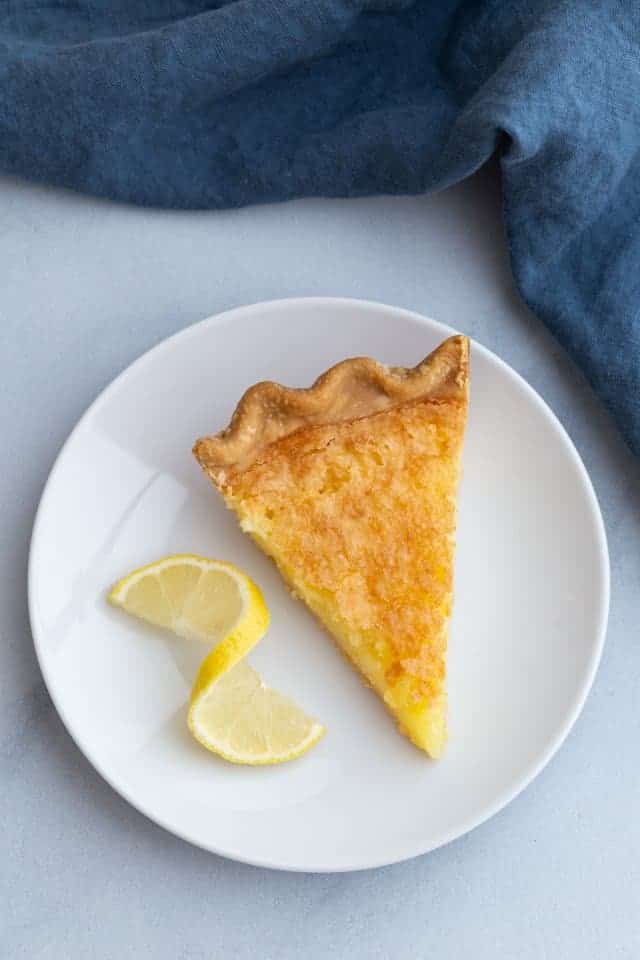 Overhead view of a single slice of lemon chess pie on a white plate.
