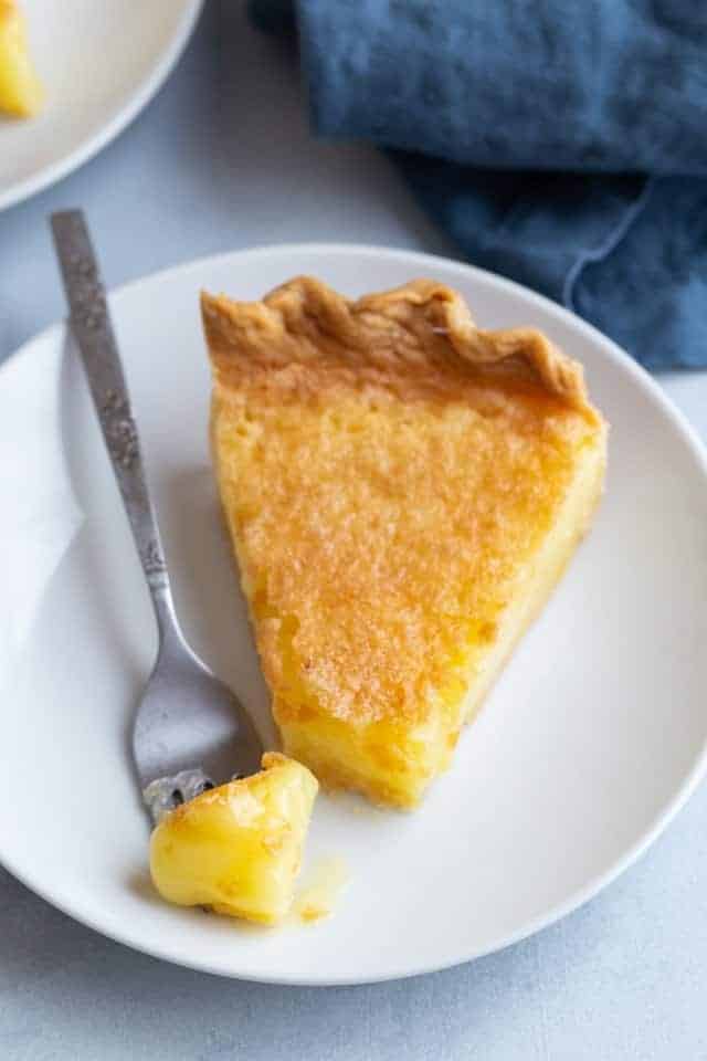 Angled view of a slice of lemon chess pie with a fork taking a bite out.