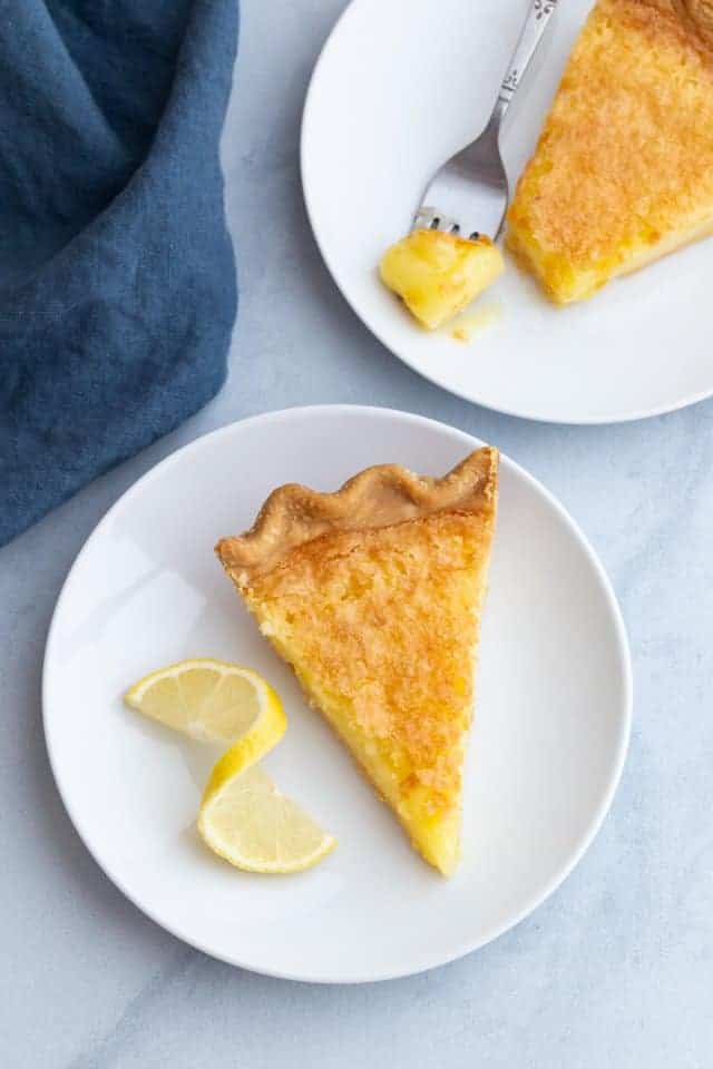 Overhead view of two slices of lemon chess pie on white plates.