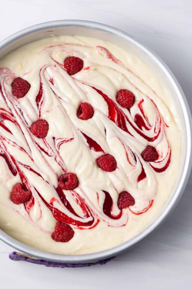 Lemon cake batter with fresh raspberries and raspberry swirl in the batter