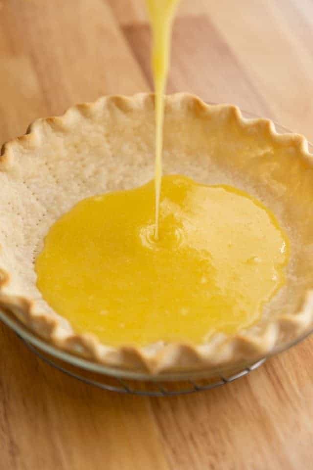 angled view of lemon filling being poured into a pie crust