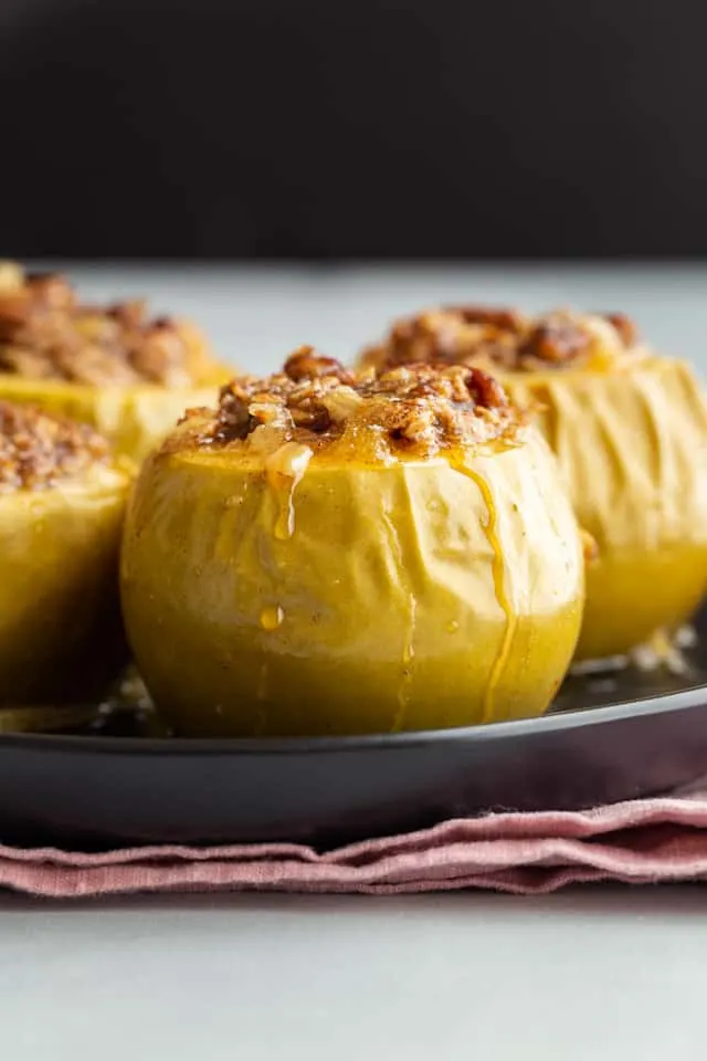 side view of baked apples on a black plate