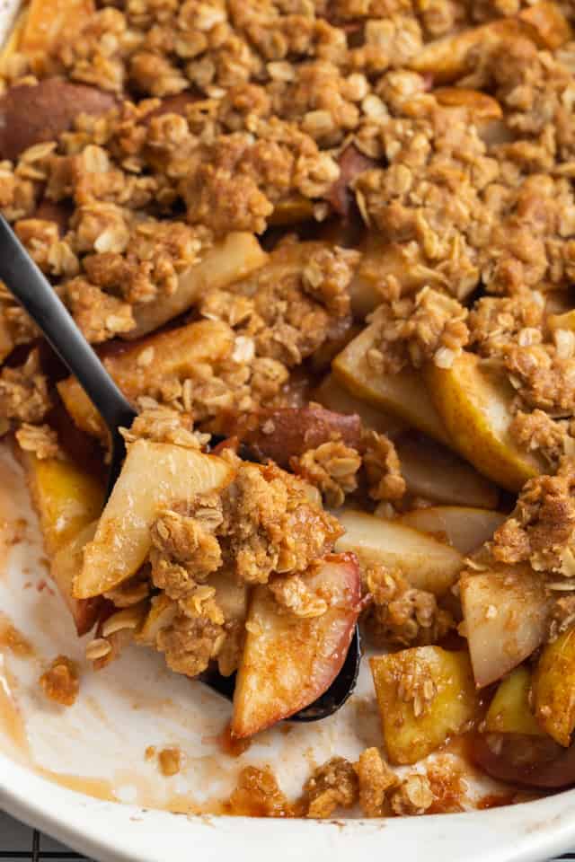 close up of pear crisp being spooned out of a pan