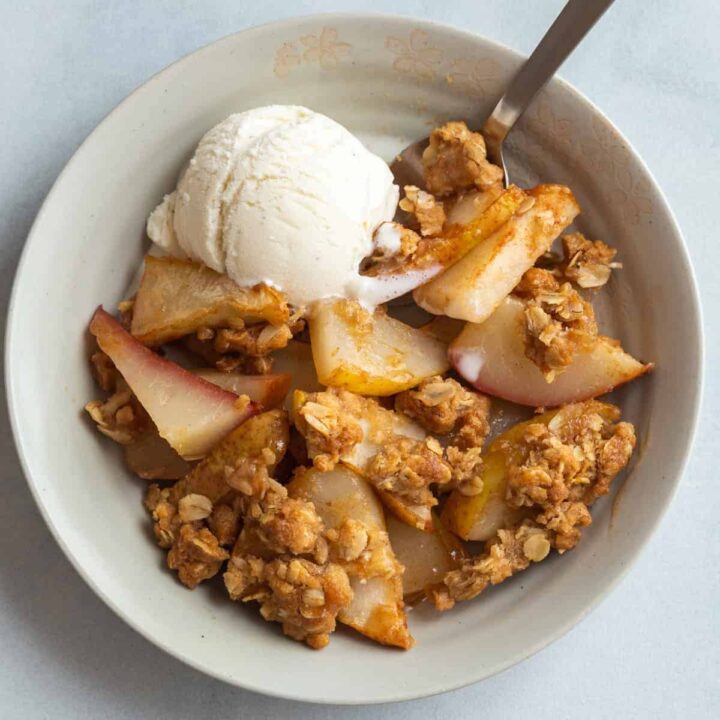 overhead view of pear crisp in a bowl with a scoop of ice cream