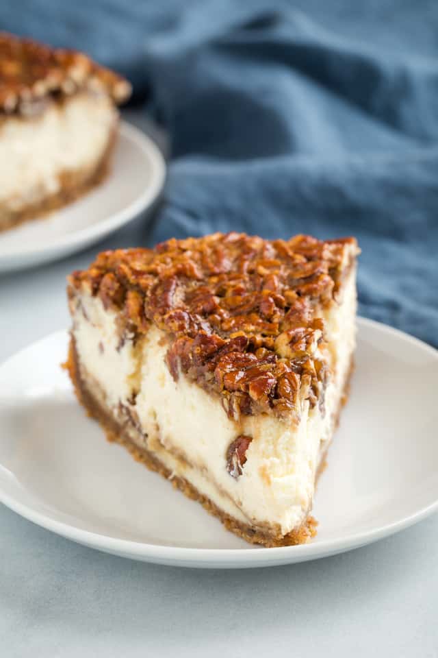 front view of a slice of pecan pie cheesecake on a white plate