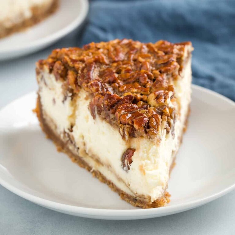 front view of a slice of pecan pie cheesecake on a white plate