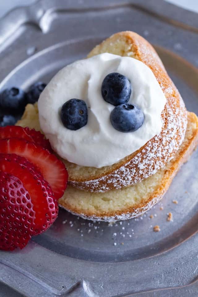 overhead of two sour cream pound cake slices topped with whipped cream and berries