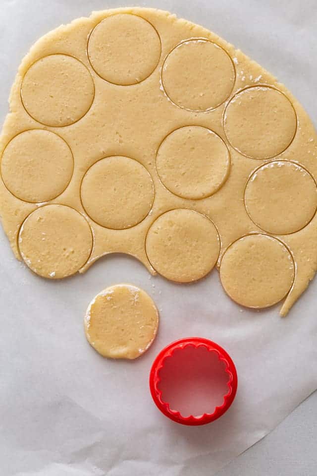 basic butter cookie dough being cut out with round cookie cutter