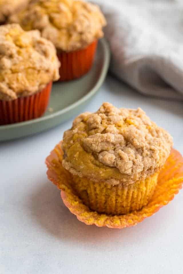 high angled view of a pumpkin muffin with the paper liner being torn away