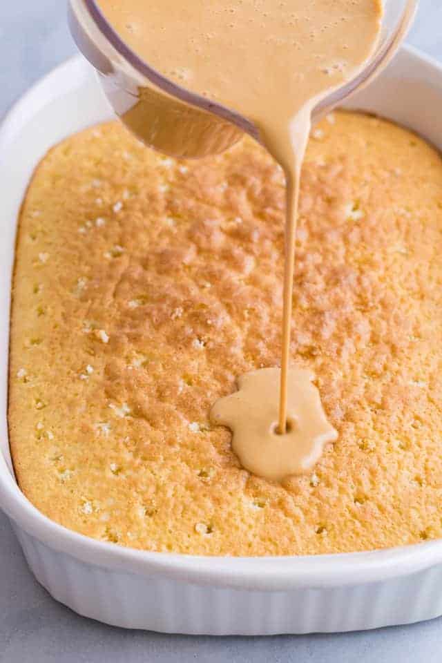 milk syrup being poured over sponge cake