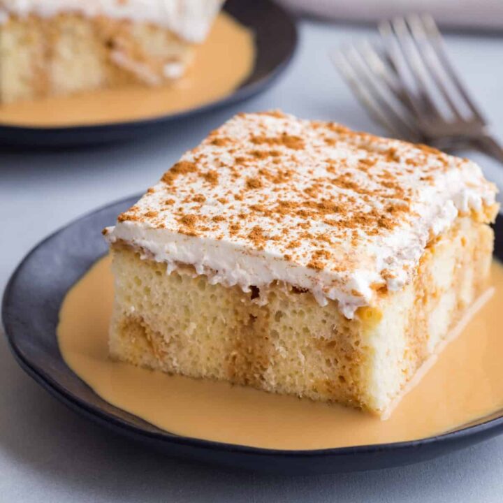 side view of tres leches cake on a dark blue plate