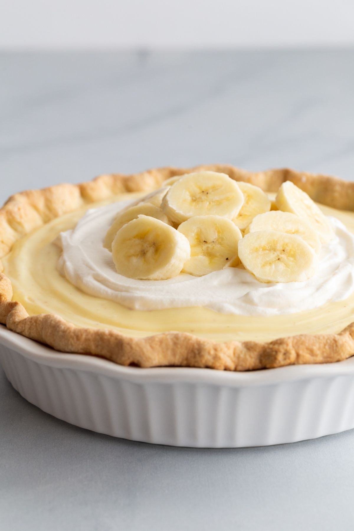 High angle view of banana cream pie in a white pie dish.