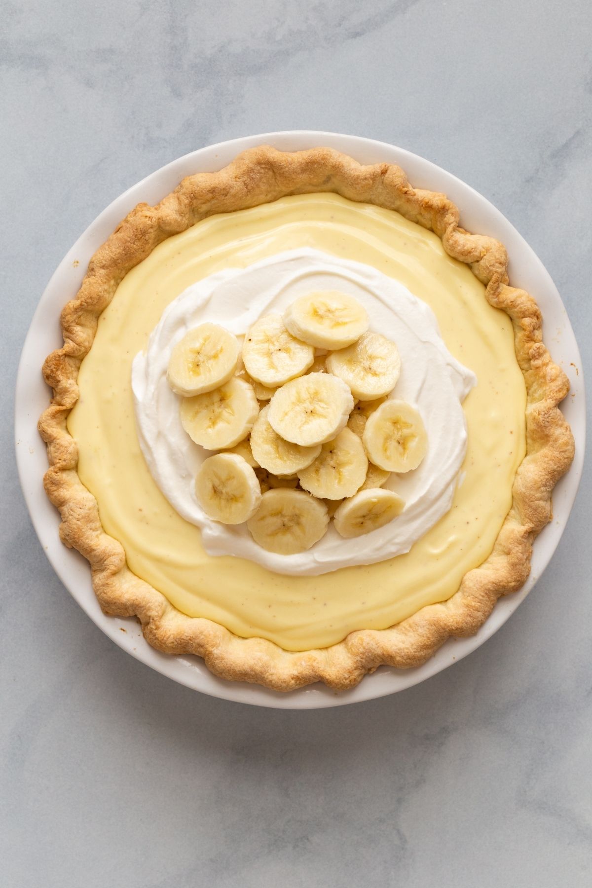 Overhead view of banana cream pie in a white pie dish.