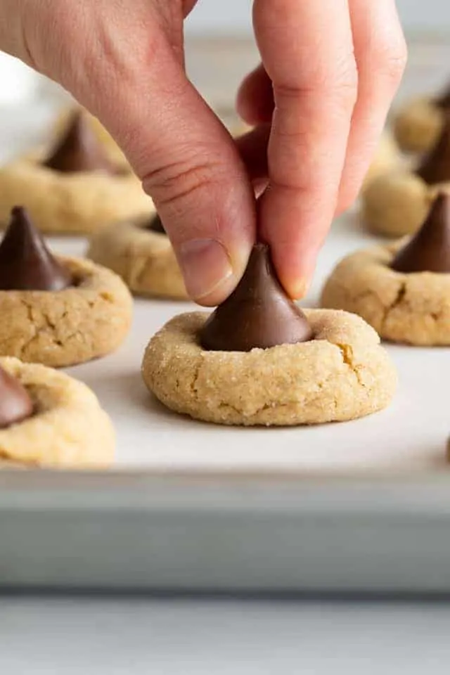 a Hershey kiss being pressed in peanut butter cookie