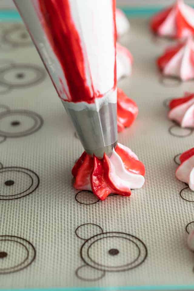 peppermint meringue being piped on silicone mat