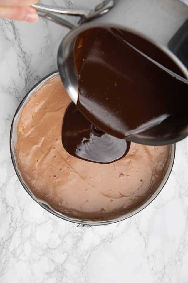 Nutella ganach being poured over triple Nutella mousse cake