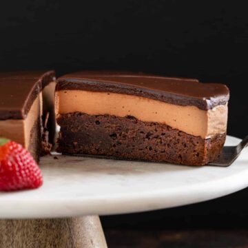 Triple Nutella mousse cake on a cake plate with a slice being taken out.