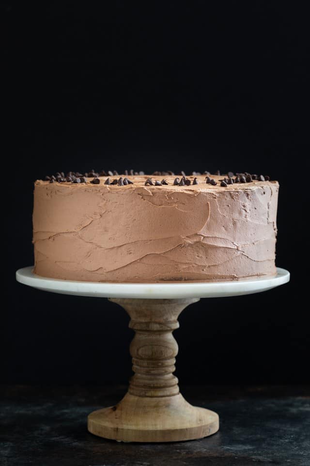 Chocolate cake on a wooden cake plate with a marble top
