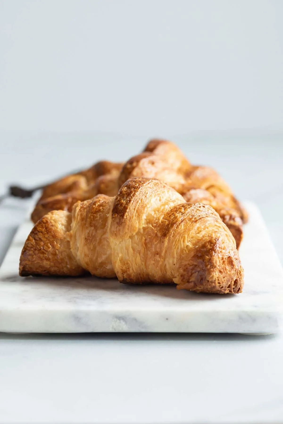 Front view of three croissants on a marble slab