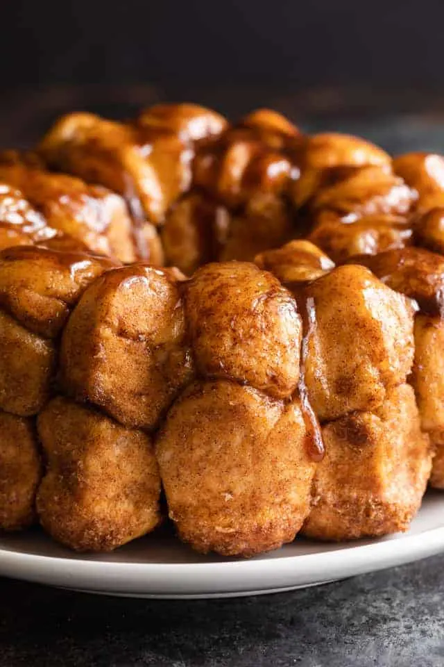 monkey bread on white plate with drippy caramel