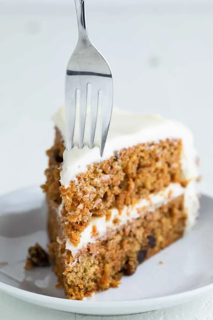 slice of carrot cake on a white plate with a fork