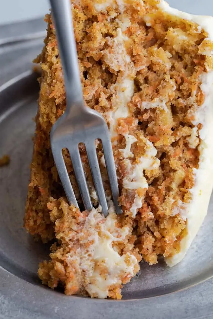 slice of pineapple carrot cake with a fork taking a bite out