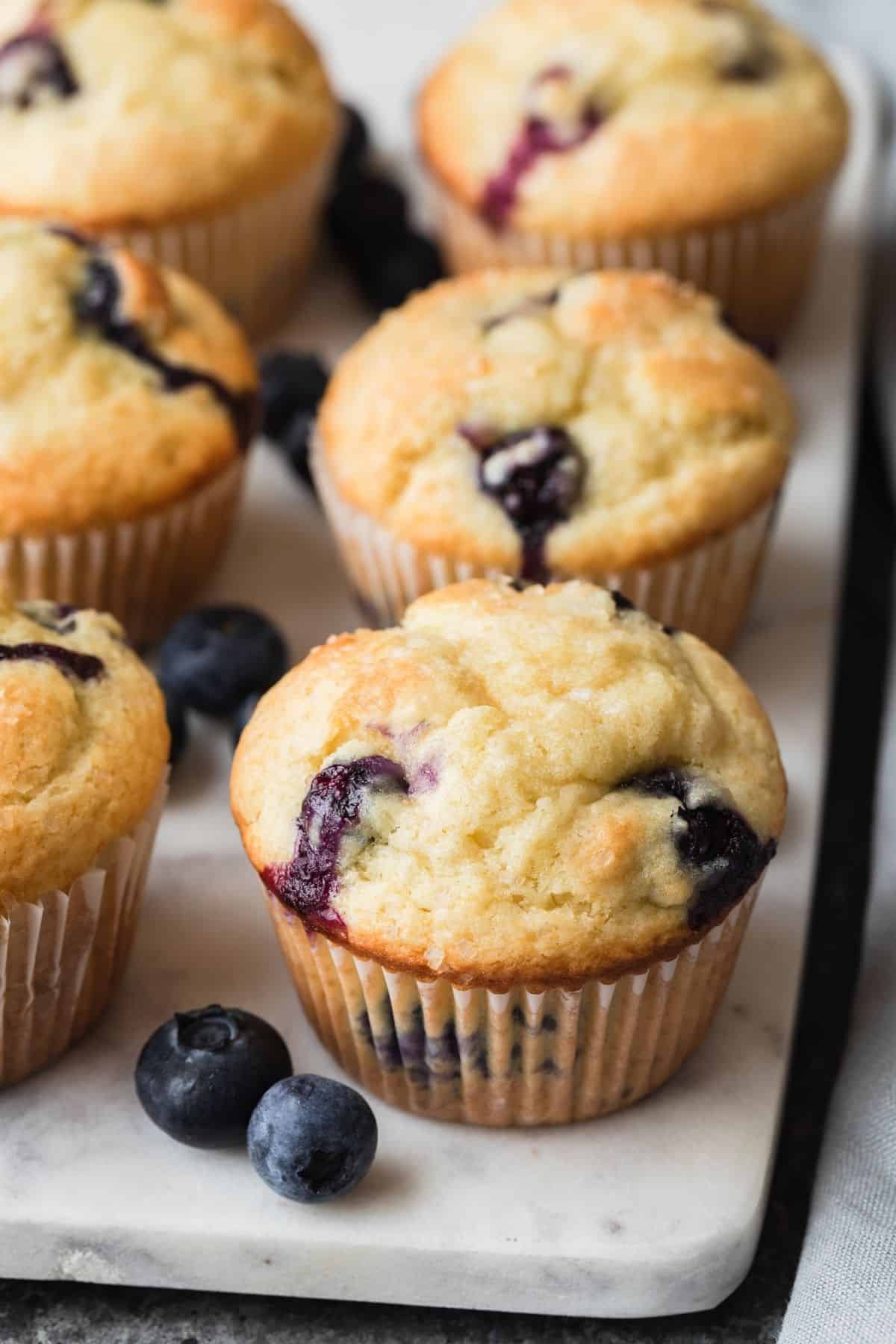 angled view of blueberry muffins on a marble board