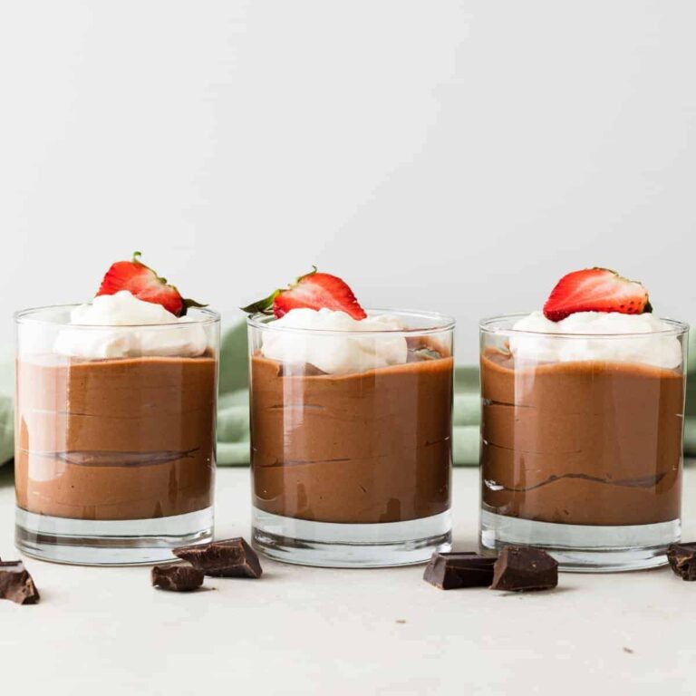 side view of classic French chocolate mousse in glass cups with whipped cream and strawberries
