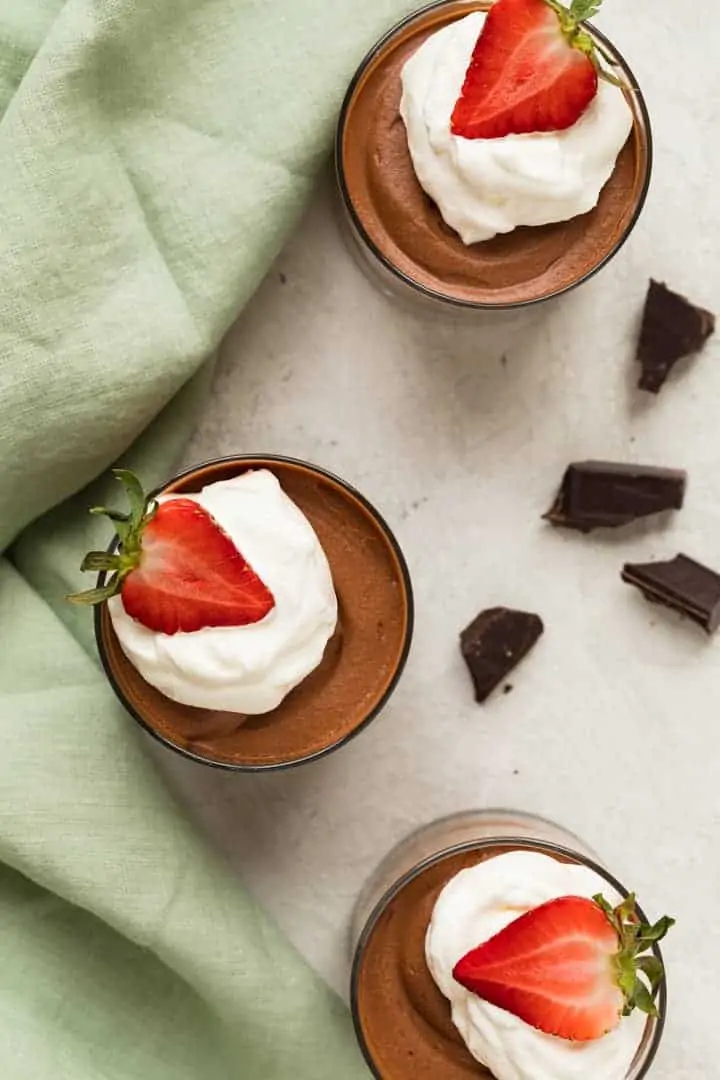 overhead of classic chocolate mousse with whipped cream and strawberries in glass cups