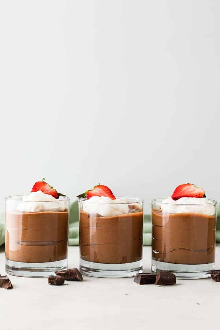 side view of classic French chocolate mousse in glass cups with whipped cream and strawberries