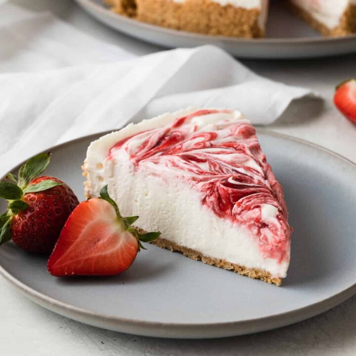 side view of a slice of no bake cheesecake on a light blue plate with fresh strawberries