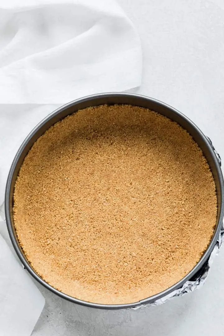 overhead of graham cracker crust in a springform pan