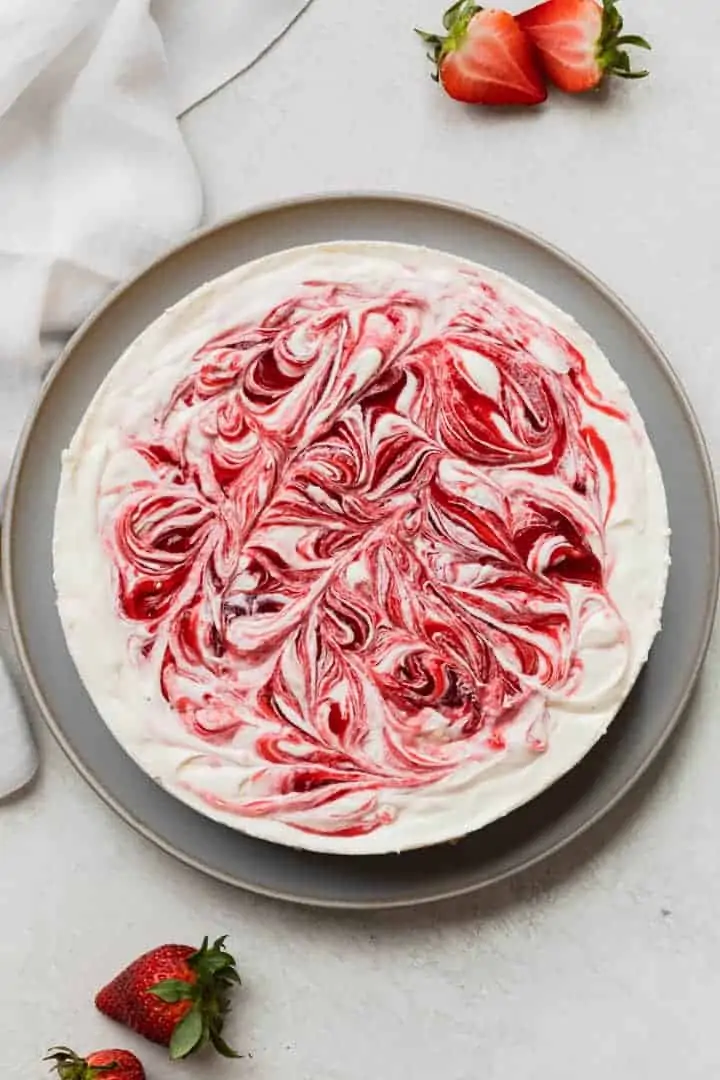 overhead view of no bake strawberry cheesecake on a light blue platter with fresh strawberries