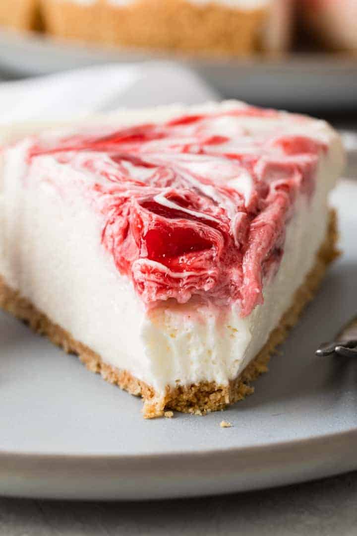 close up view of slice of no bake strawberry cheesecake with a bite taken out