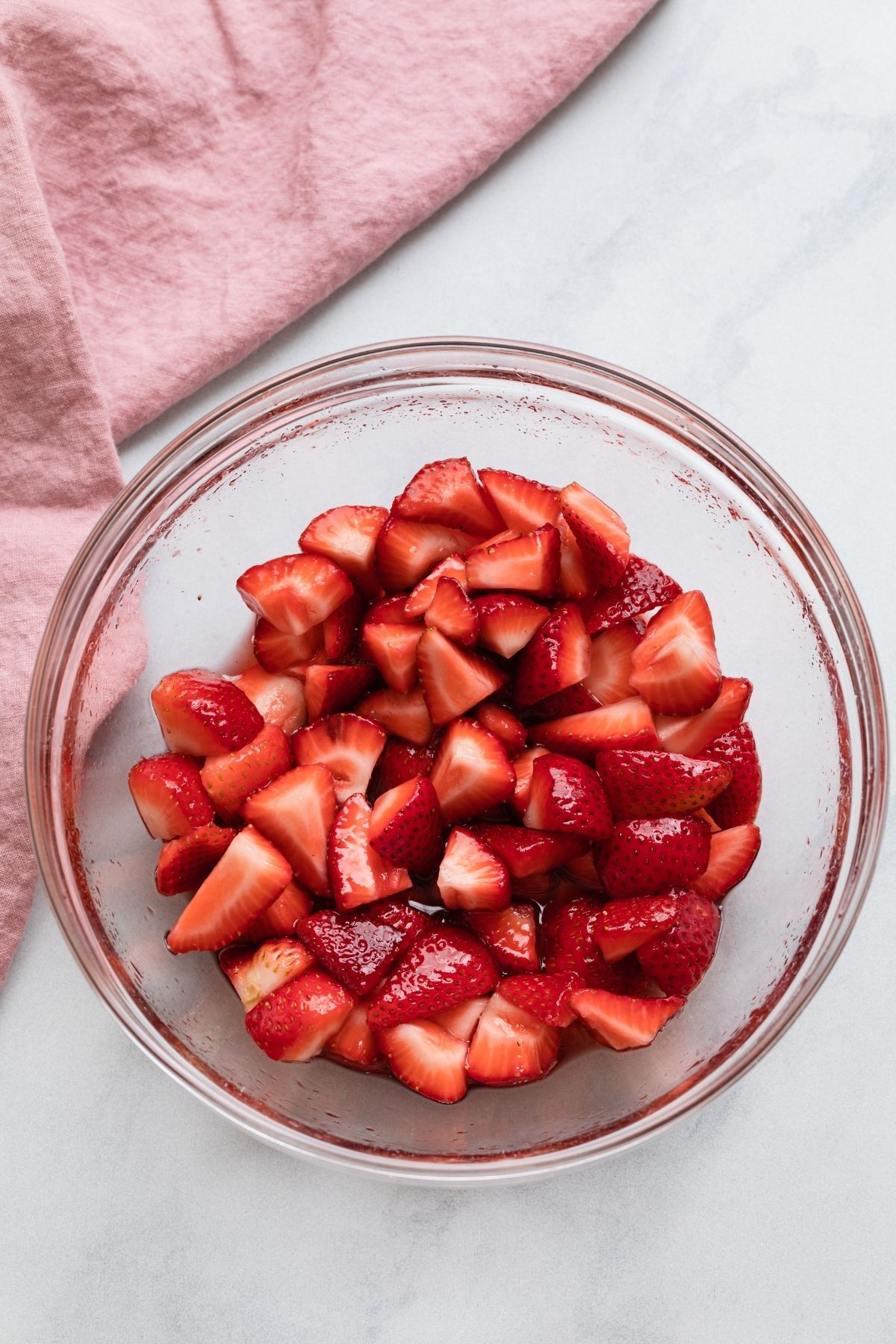 Sweetened strawberries in glass bowl.