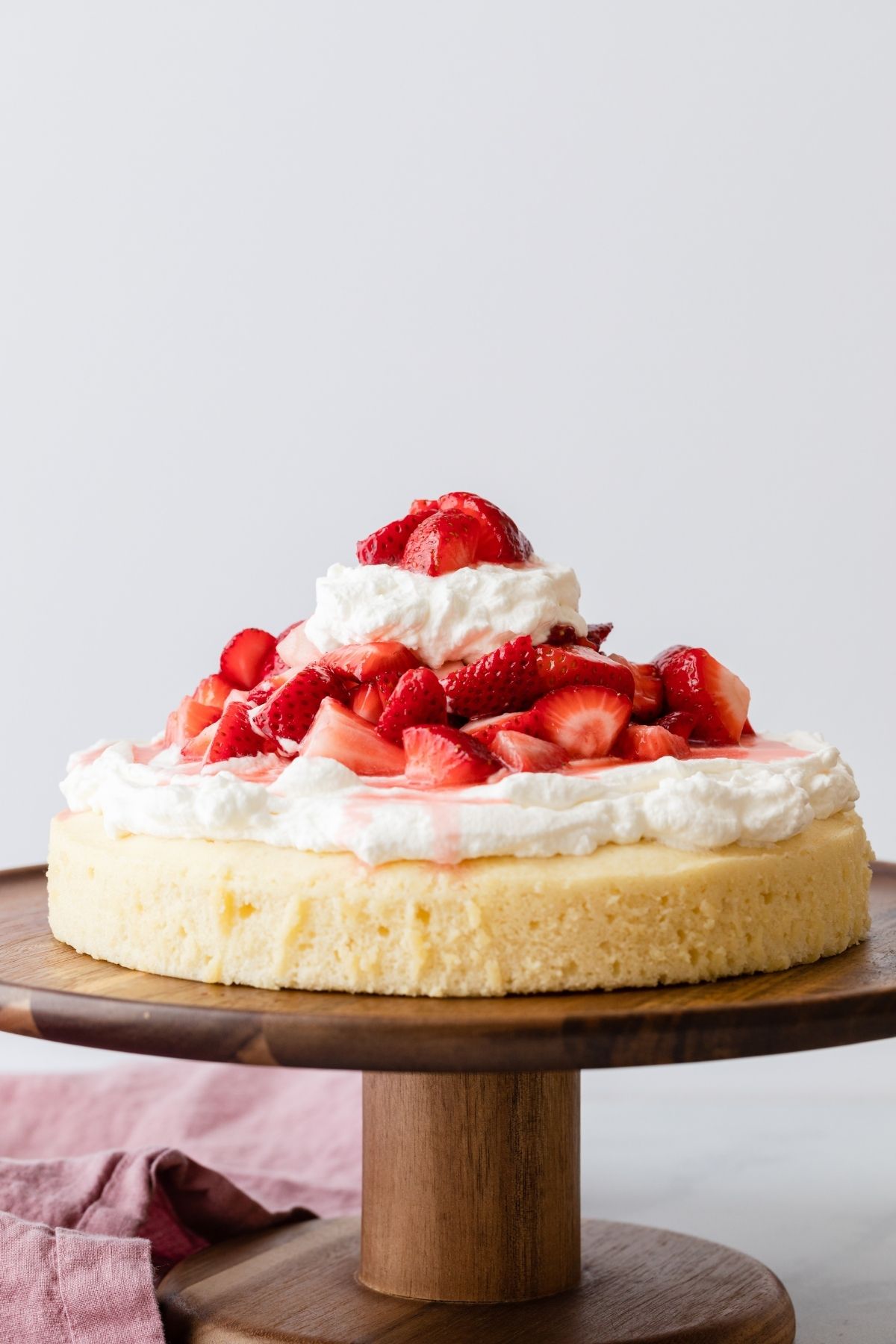 Single layer strawberry shortcake cake on a wooden cake stand.