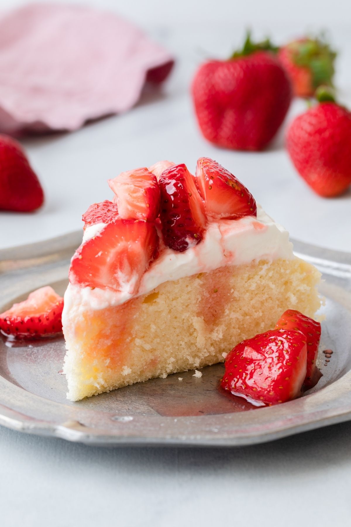 Slice of strawberry shortcake cake on a pewter plate.