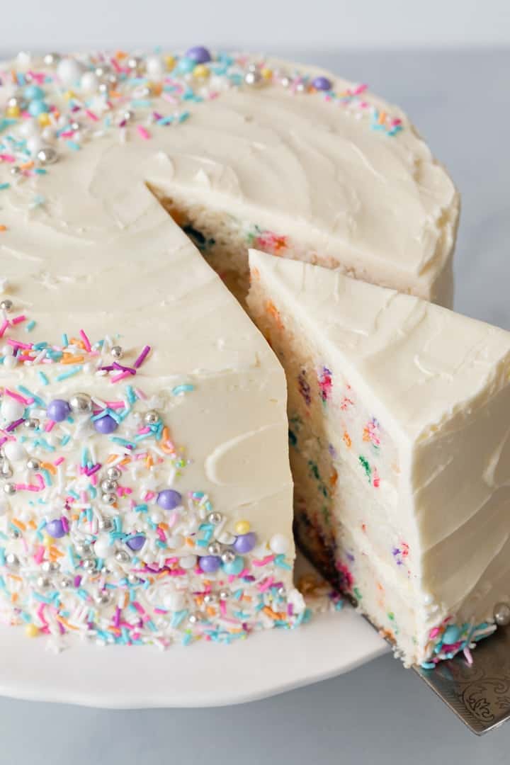 angled view of funfetti cake with slice being taken out