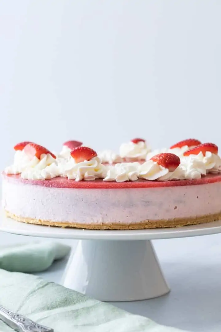 front of a strawberry mousse cake on a white cake stand