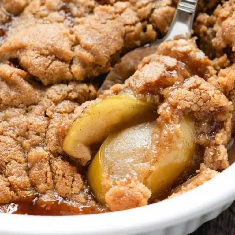 apple crumble in a casserole dish with a spoon scooping some out