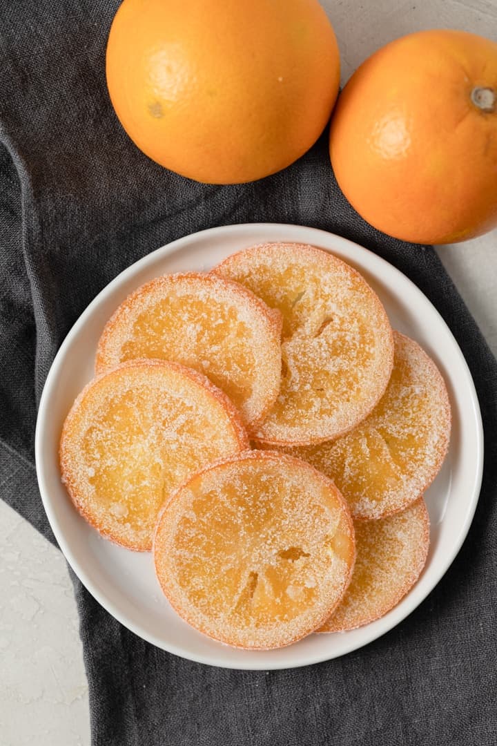 overhead of candied orange slices arranged on a white plate