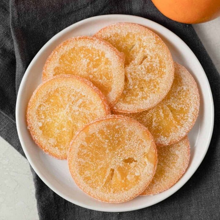 overhead of candied orange slices arranged on a white plate