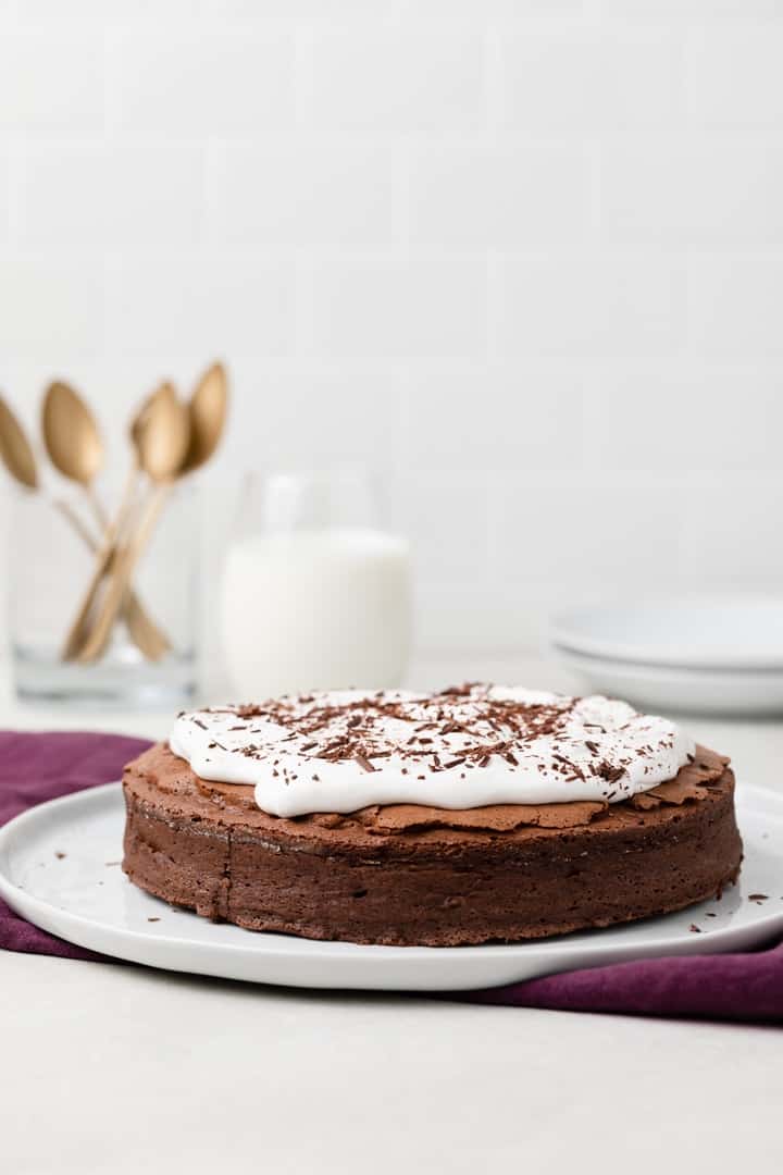 side view of flourless chocolate cake on white serving plate